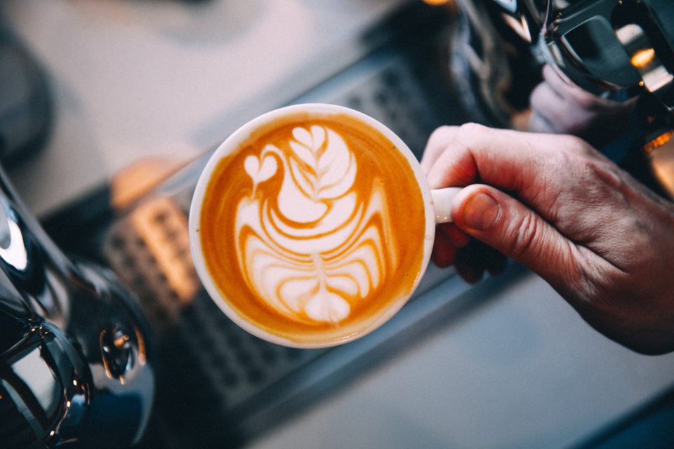 A latte with rosetta art being served at the counter