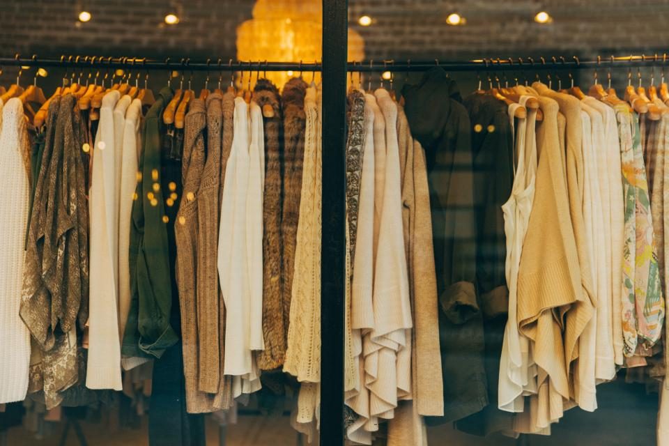 Clothes hanging on rails in a warmly lit boutique