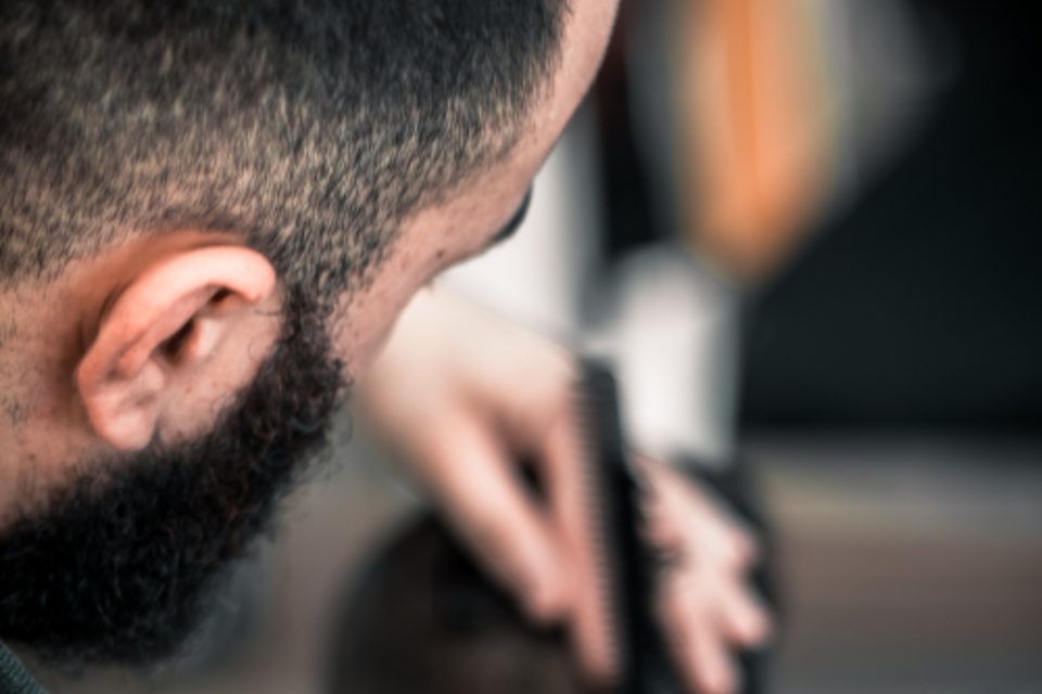 A barber using clippers on a client’s fade