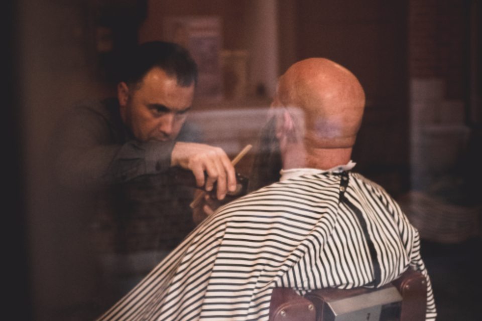 A barber at work, seen through the shop window