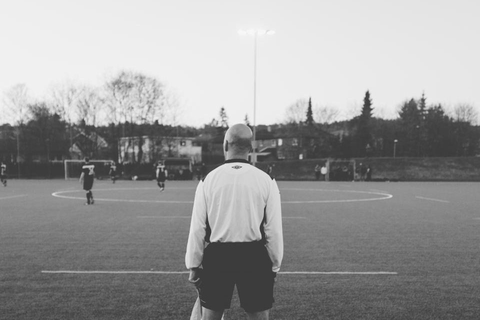 A coach watching a junior football game from the sideline