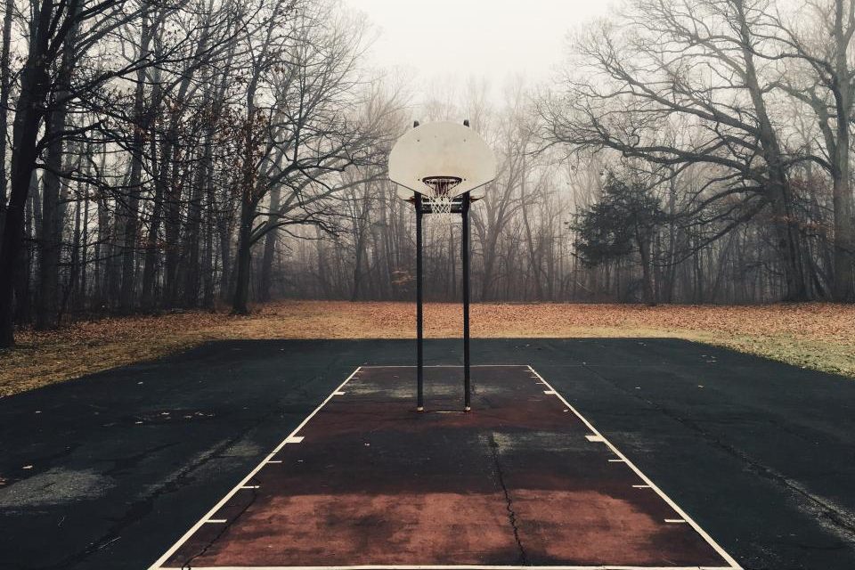 A misty, empty basketball court surrounded by trees